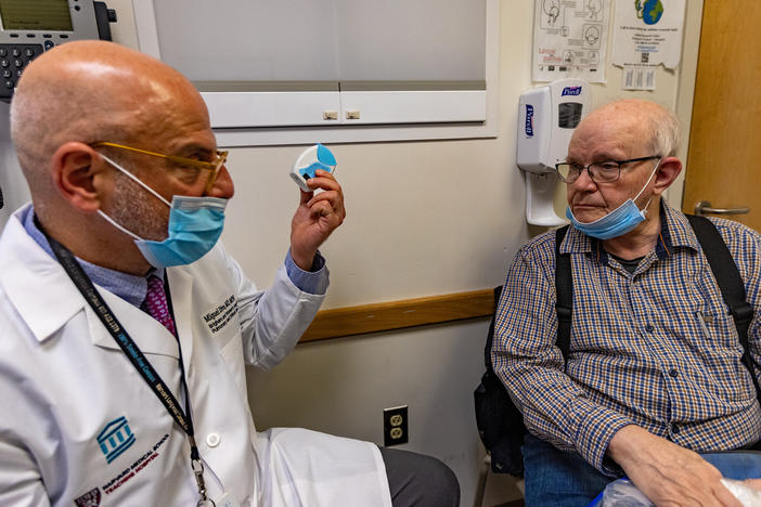 Miguel Divo shows his patient, Joel Rubinstein, a dry powder inhaler. It's an alternative to some puff inhalers that emit potent greenhouse gases, but is equally effective for many patients with asthma.
