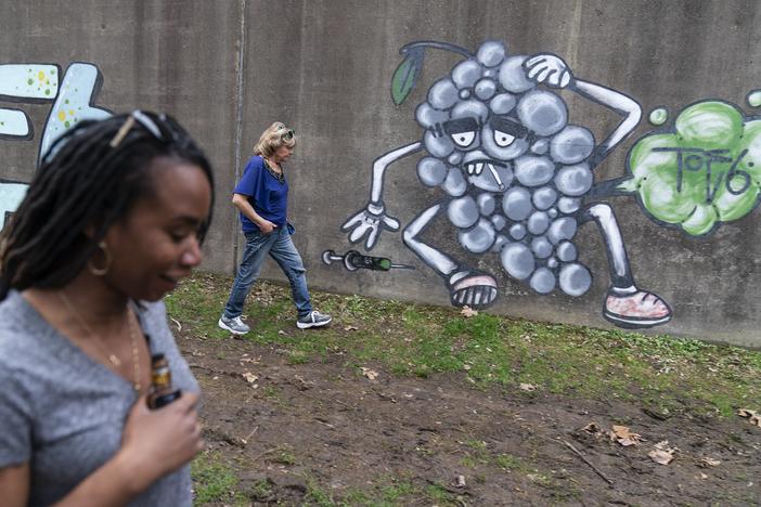 Sue Howland, right, and Larrecsa Cox walk past addiction-themed graffiti 