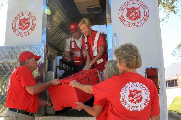 Volunteers unload cargo from a Salvation Army truck.