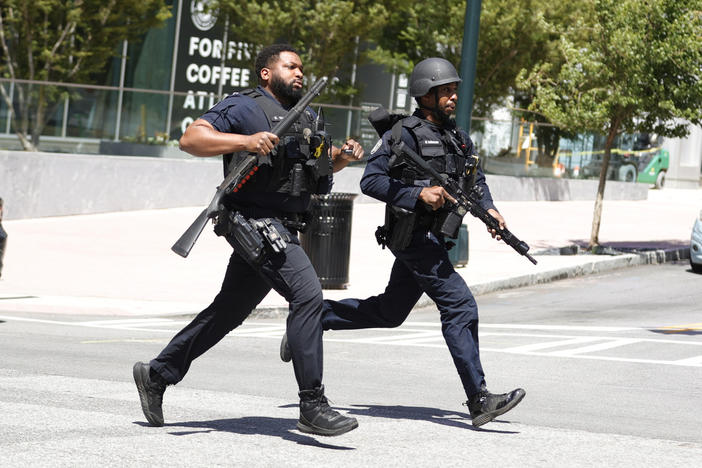 Law enforcement officers run near the scene of an active shooter on Wednesday, May 3, 2023 in Atlanta. Atlanta police said there had been no additional shots fired since the initial shooting unfolded inside a building in a commercial area with many office towers and high-rise apartments. 