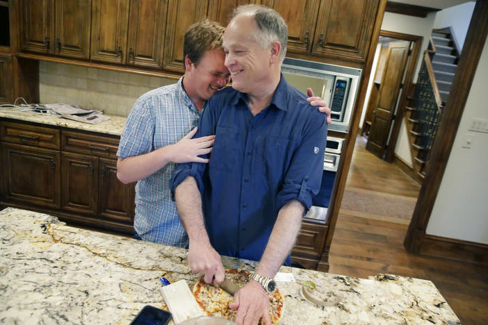 A son hugs his father in a kitchen