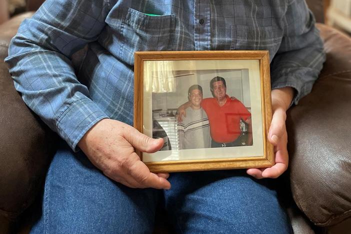Matthew Pesce holds a framed photo of him and his son, who died by suicide.