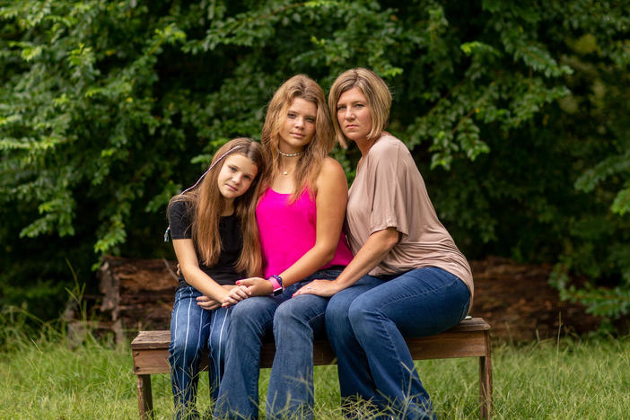 Allie Henderson with her sister Claire (left) and her mom, LeAnn, outside their home recently in Terry, Miss. "I want people to get vaccinated — because I know what it feels like," Allie says of her near-fatal encounter with COVID-19 this year.
