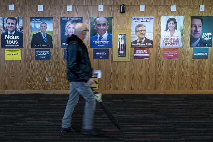 A French voter passes identification posters on his way to vote in the first round of the 2022 French presidential election, in Montreal, Saturday, April 9, 2022.