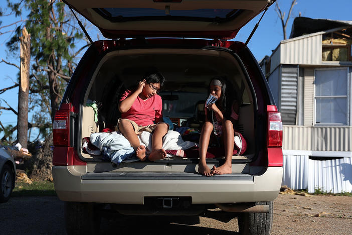 Carlos and Jessica Deviana sit in the back of their father's SUV, which they were using as a bedroom after Hurricane Michael destroyed their home in Panama City, Fla., in October 2018.
