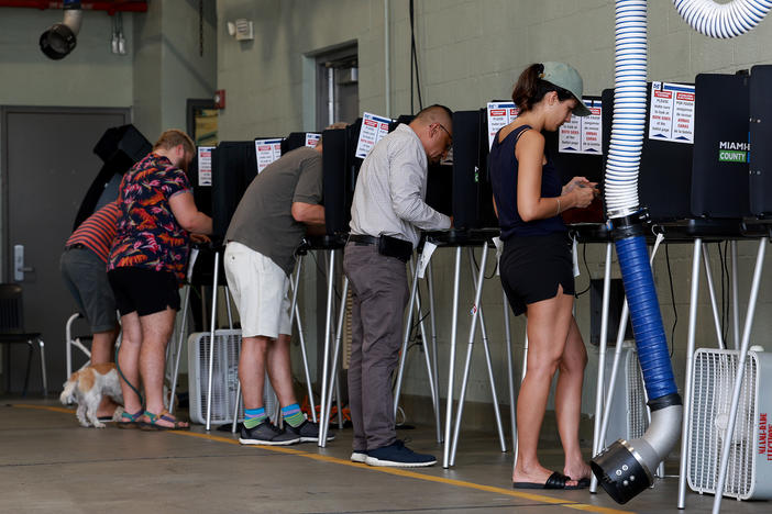 Voters cast their ballots at a polling station set up in a fire station on Aug. 23 in Miami Beach, Fla.