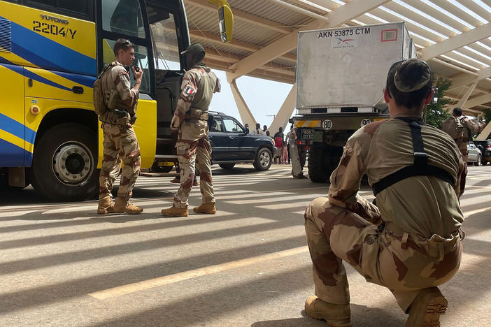 French soldiers assist mostly French nationals in a bus waiting to be airlifted back to France on a French military aircraft, at the international Airport in Niamey, Niger, Tuesday, Aug. 1, 2023.