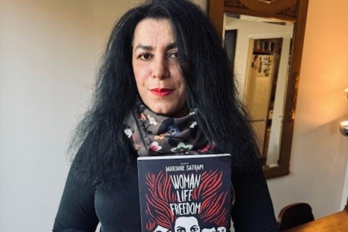 <strong></strong>Marjane Satrapi, a graphic novelist, holds her latest book <em>Woman, Life, Freedom</em>, in her home in Paris, France.