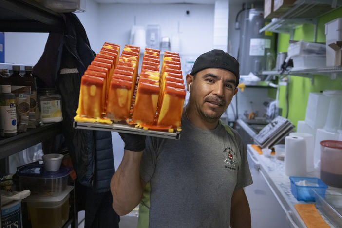 Manuel Vazquez, owner of Coya's artisan ice cream, poses for a photo as he carries a tray of ice pops in the kitchen of his shop in Fort Myers, Florida, U.S., February 26, 2024.