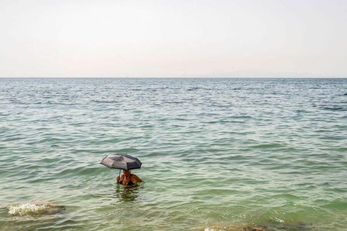A woman takes refuge during Greece's July 2023 heat wave. El Niño helped drive global temperatures to new heights, making it the hottest year on record.