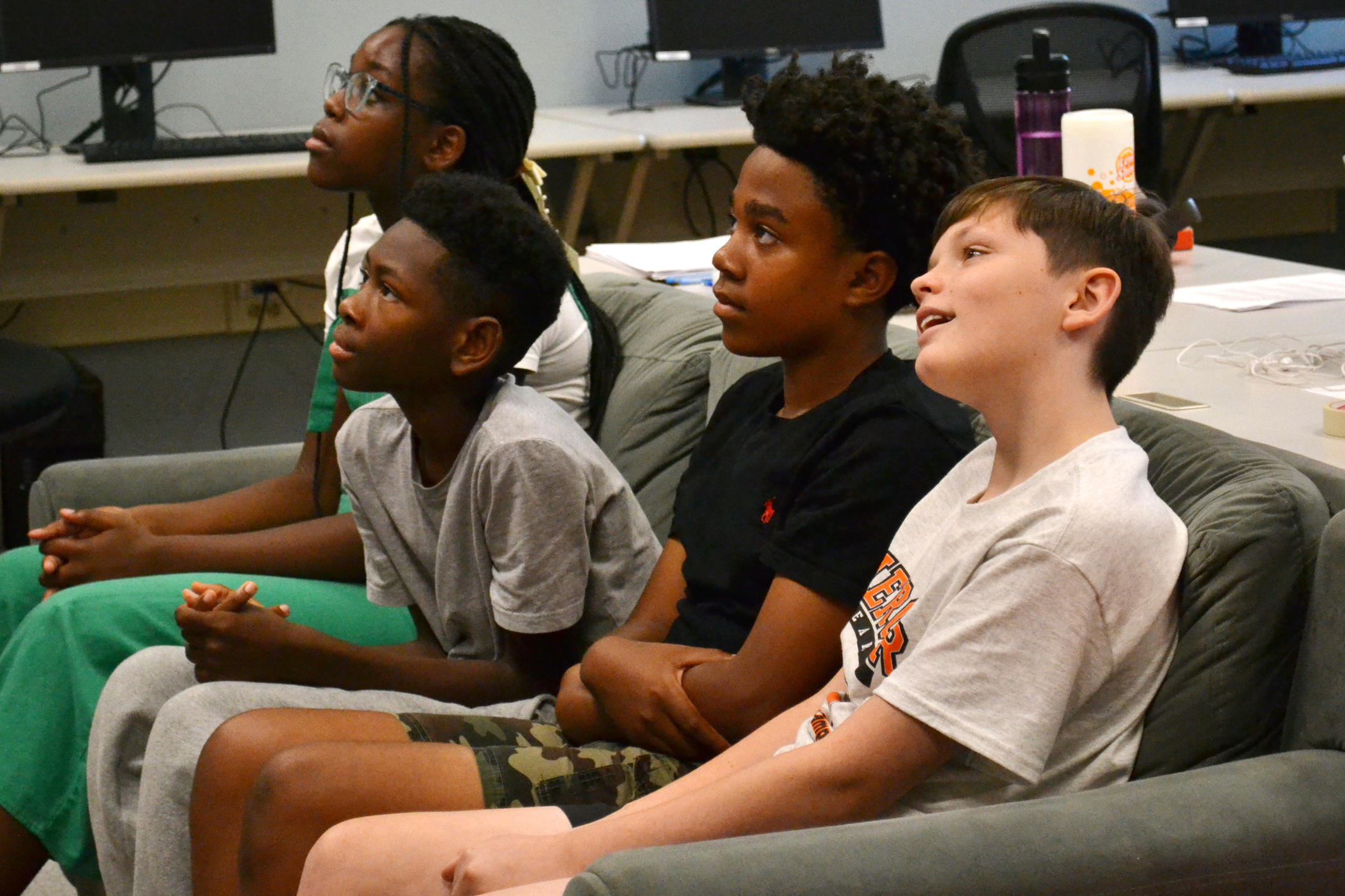 Students in AI Camp react to teacher Joe Finkelstien prompting an AI on the projector. From left to right, campers from the week of June 10, 2024: Christabelle Kabuye, Bryson Brandon, Aiden Wright, and Lawson Surles.