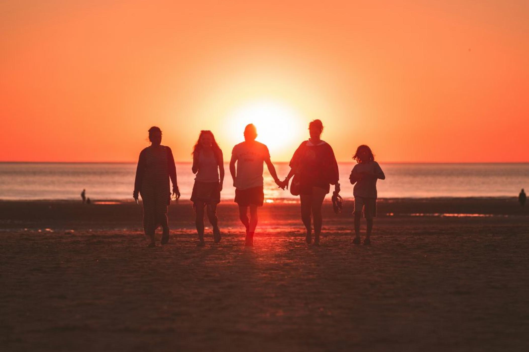 Silhouettes of a family of 5 on the beach at sunset.