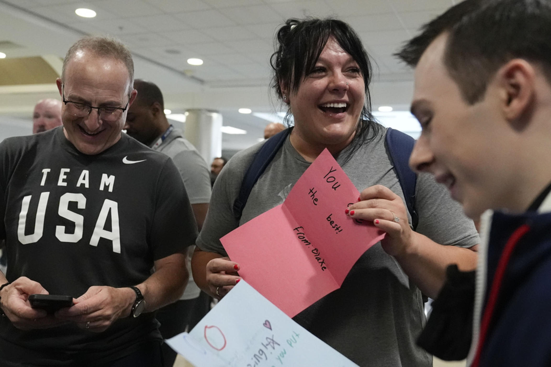Team USA weightlifting athlete, Mary Theisen smiles as they read an encouraging note from a local high schooler as they depart from the airport for the Summer Olympic Games, on Wednesday, July 17, 2024, in Atlanta. (AP Photo/Brynn Anderson)