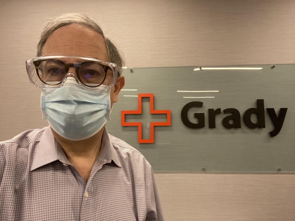 Dr. Carlos del Rio wears a mask in front of a Grady hospital sign.