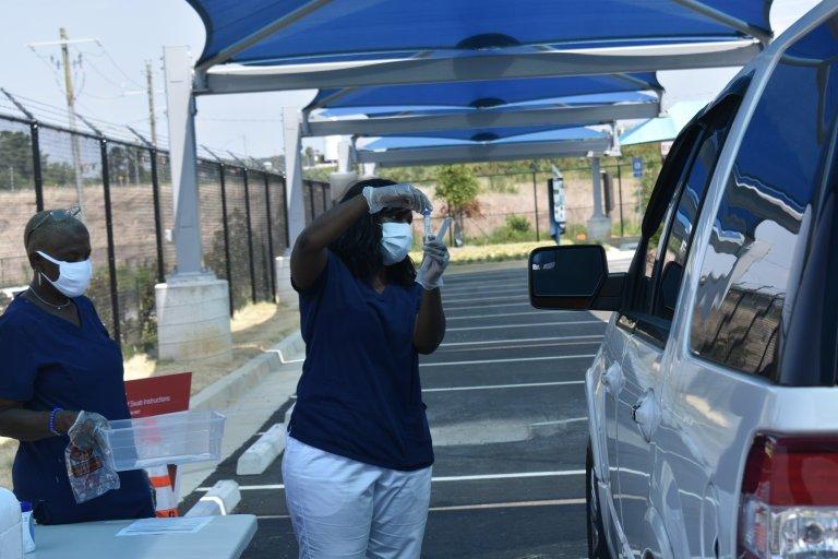 A public health worker collects a sample from someone at a mega testing site at Atlanta Hartsfield-Jackson Airport last month. The site will close Friday. 