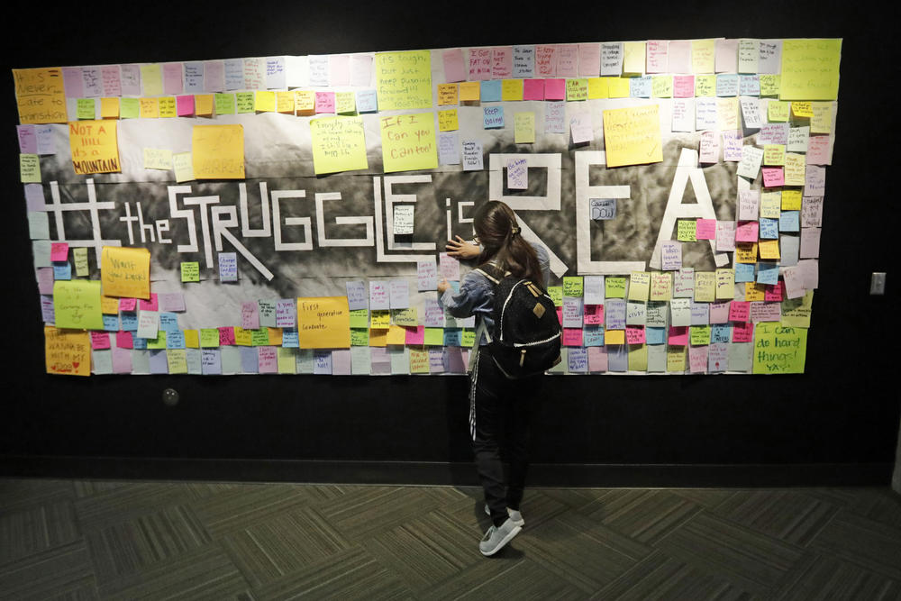 In this Nov. 14, 2019, photo, a student attaches a note to the Resilience Project board on the campus of Utah Valley University, in Orem, Utah.