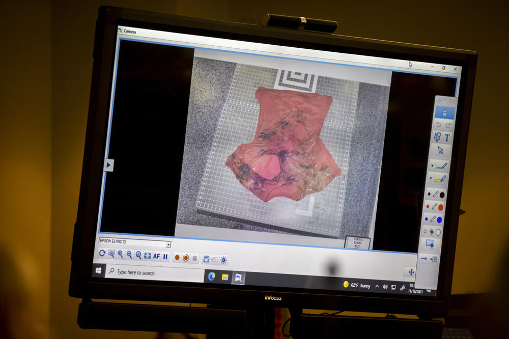 Prosecutor Linda Dunikoski shows a photo of the bloody tee shirt with a large hole in it during Dr. Edmund R. Donoghue testimony, during the trial of Greg McMichael and his son, Travis McMichael, and a neighbor, William "Roddie" Bryan in the Glynn County Courthouse, Tuesday, Nov. 16, 2021, in Brunswick, Ga.