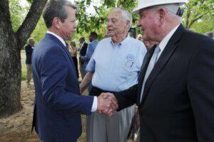  Gov. Brian Kemp and University System of Georgia Chancellor Sonny Perdue shake hands at a groundbreaking ceremony for a meat snack company in Perry. 