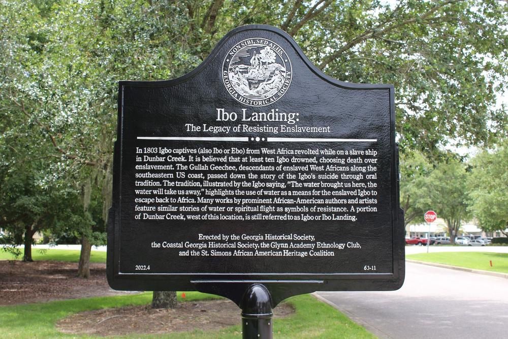 A black plaque with white inscribed lettering gives information about Igbo Landing.