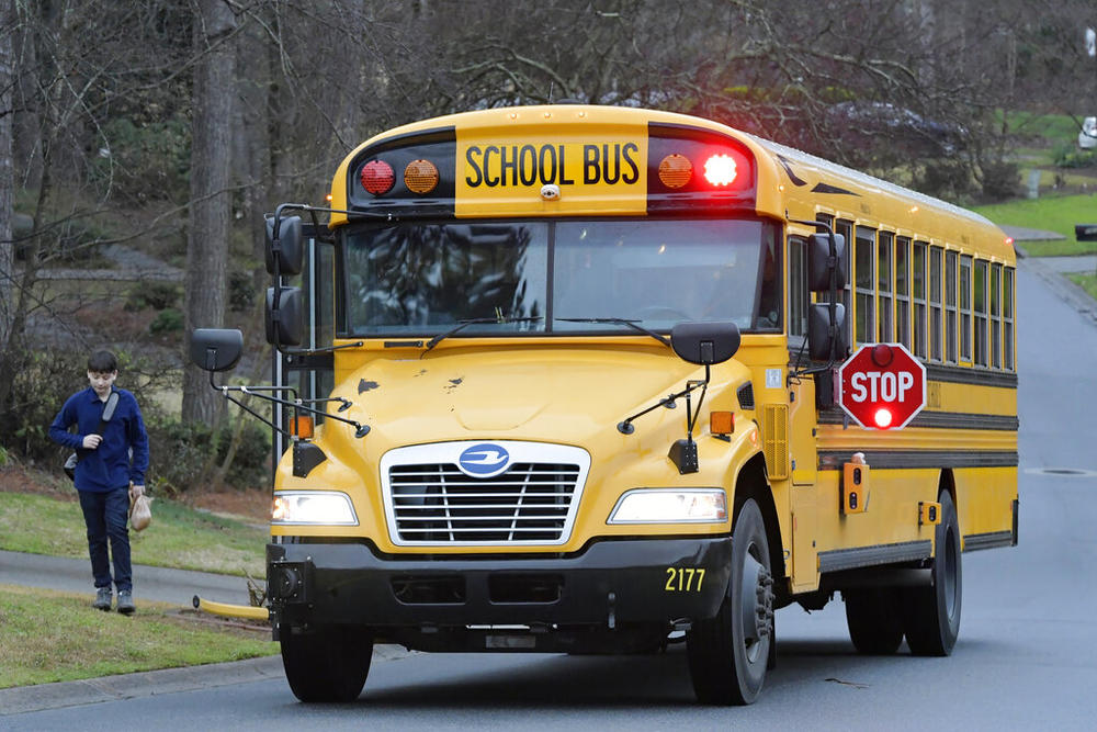 A Cobb County School bus moves on street Friday, March 13, 2020, in Kennesaw, Ga. 