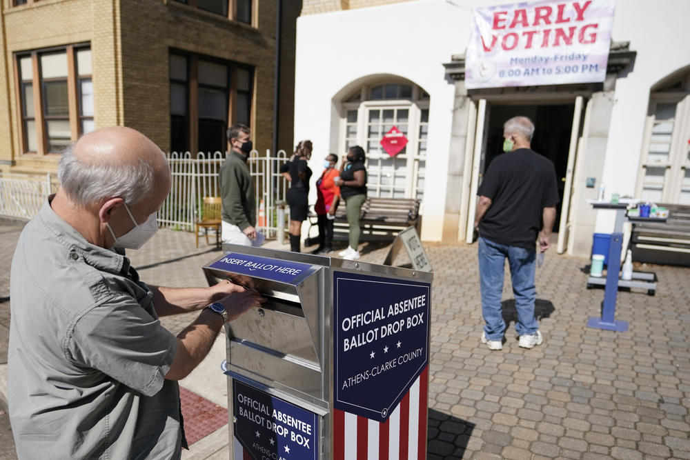 A voter drops their ballot off during early voting, Monday, Oct. 19, 2020, in Athens, Ga. With record turnout expected for this year’s presidential election and fears about exposure to the coronavirus, election officials and advocacy groups have been encouraging people to vote early, either in person or by absentee ballot.