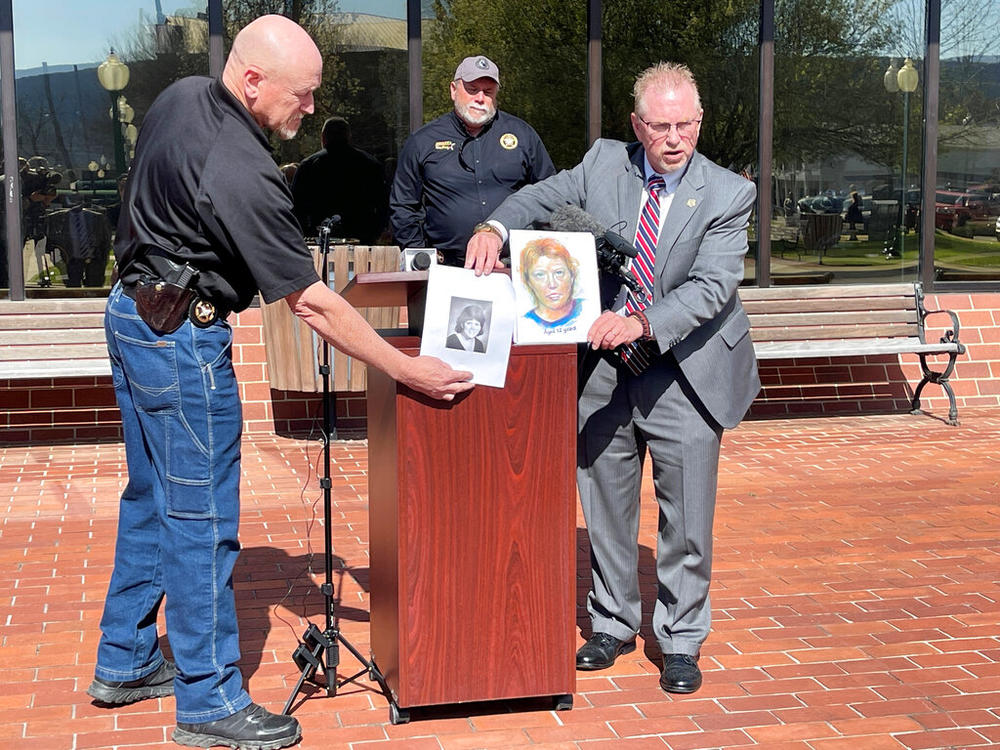 In this photo provided by The Georgia Bureau of Investigation investigators hold a photo of Stacey Lyn Chahorski, left, of Norton Shores, Mich., and a composite sketch of her in Trenton, Ga., March 24, 2022. Georgia and federal officials said on Tuesday, Sept. 6, 2022, that DNA has identified a deceased truck driver as the man who killed the young woman in 1988 in the state's far northwest corner. Officials said genetic genealogy points to Henry Fredrick “Hoss” Wise as the killer of Chahorski. (The Georgia 