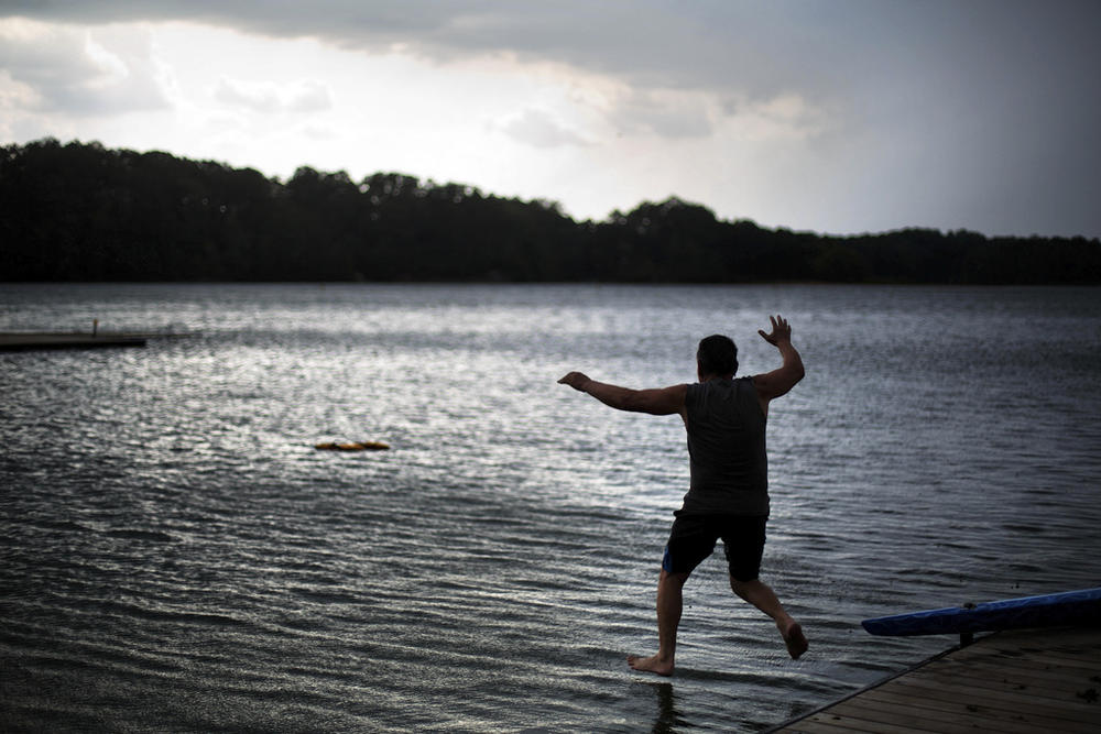 Radko Jonas jumps into the water to retrieve a life vest that blew away as rain clouds approach at Lake Lanier on July 19, 2016, in Gainesville, Ga. The U.S. Army Corps of Engineers said Friday, March 10, 2023, it is pausing a plan to rename the lake and the associated Buford Dam, both named after former Confederate soldiers, after local residents objected. 