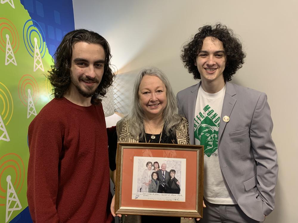 Sheri Mann Stewart (center), with sons Royce Mann (left) and Tendal Mann, holds a family photo with Jimmy and Rosalynn Carter.