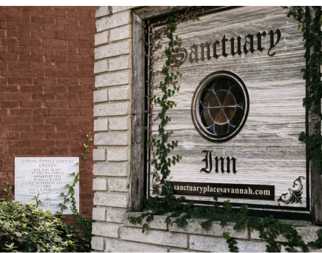 A plaque commemorating the Garvin Temple Baptist Church, a historical Black church, is still visible behind the sign for the Sanctuary Inn.