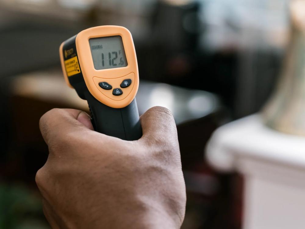 Using an infrared thermometer to measure the heat put out by an LED light bulb.