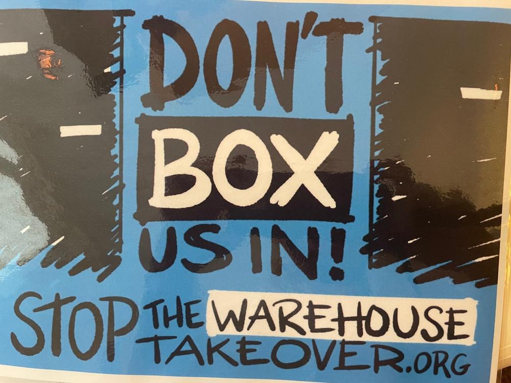 A sign reads "DON'T BOX US IN! STOP THE WAREHOUSE TAKEOVER.ORG"