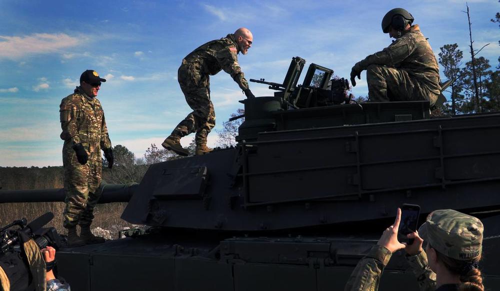 Jay Tenison, a military veteran currently fighting Stage IV stomach cancer, center, climbs onto a tank Tuesday afternoon at Fort Moore, Georgia.