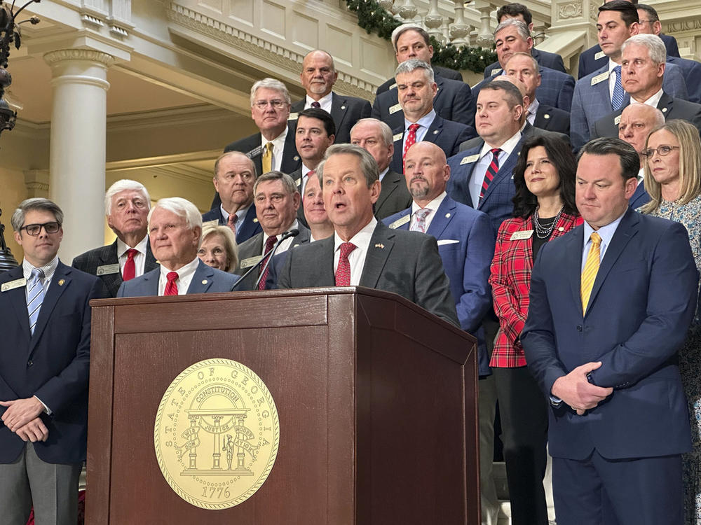 Georgia Gov. Brian Kemp, flanked by Republican lawmakers, speaks Monday, Dec. 4, 2023, at the Georgia Capitol in Atlanta. Kemp and Republican legislators want to make a further cut to Georgia's state income tax rate in the 2024 legislative session. 