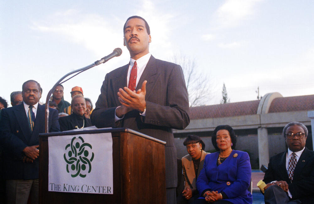 Dexter King, son of Martin Luther King Jr., speaks to the press outlining his family's plan for an interactive museum to be built at the MLK Center in Atlanta, Dec. 28, 1994. The King family has ordered all National Park Service tours of King's birthplace and tomb be stopped as the King family dispute with the government escalated on Wednesday. Coretta Scott King, right, and her daughter Bernice are seated in the background. (AP Photo/Leita Cowart)