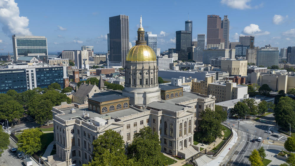 The gold dome of the Georgia Capitol gleams in the sun, Aug. 27, 2022, in front of the skyline of downtown Atlanta.