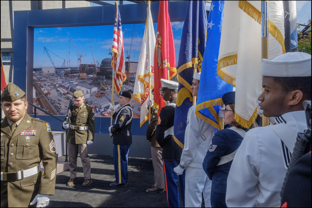An military color guard backed by a slideshow of milestones in the construction of units 3 and 4. 