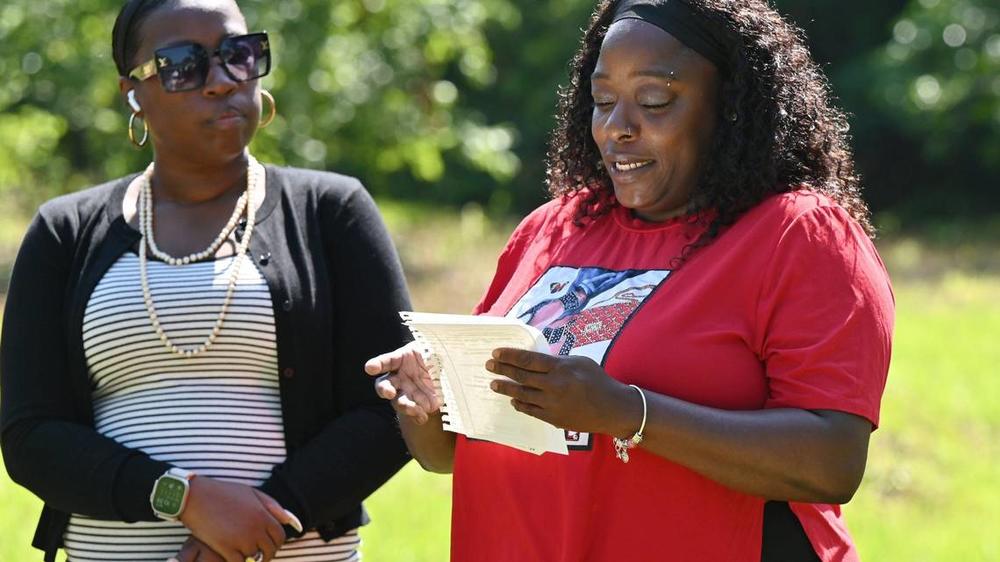 Future homeowner LaQuanda Ferguson (right) reads remarks next to Macon Area Habitat for Humanity board president Andrea Cooke during the Lynmore Estates ground blessing on Tuesday, May 28, 2024, in Macon, Georgia. Macon Area Habitat for Humanity held the ground blessing at a plot of land off of Dorothy Avenue where three future homes will be built.