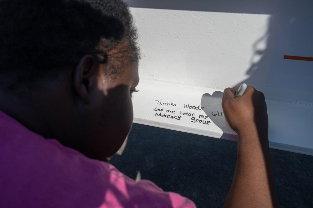 Tamika Woods with See Me Hear Me advocacy group signs the final structural beam on the new center. She hopes the center gives more people with IDD a chance to find medical care.