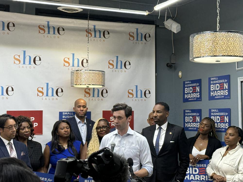 U.S. Sen. Jon Ossoff (center), flanked by Biden supporters as well as Atlanta Mayor Andre Dickens (third from right), state Sen. Jason Esteves (fourth from left) and She Salon owner Gigi Palmer (fifth from left) in Atlanta's Castleberry Hill neighborhood on Tuesday, June 25, 2024.