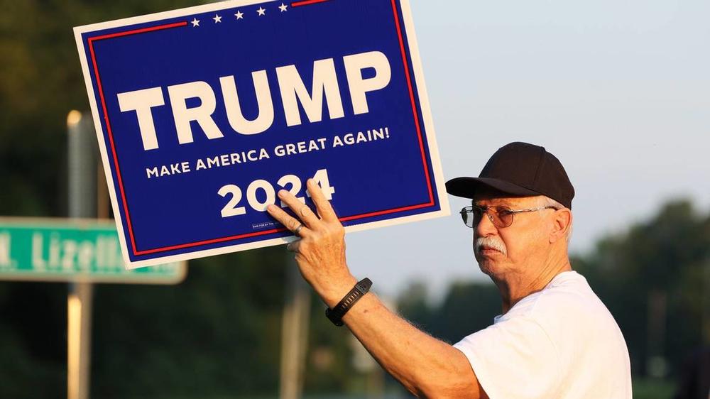 Aubrey Clark stands with a Trump 2024 sign on the side of Eisenhower Parkway on Monday, July 15, 2024, in Lizella, Georgia. A half dozen supporters, including members of the Bibb County Republican Party, gathered to show their support for former president Trump two days after an attempted assassination attempt on him in Pennsylvania. Katie Tucker/The Telegraph 