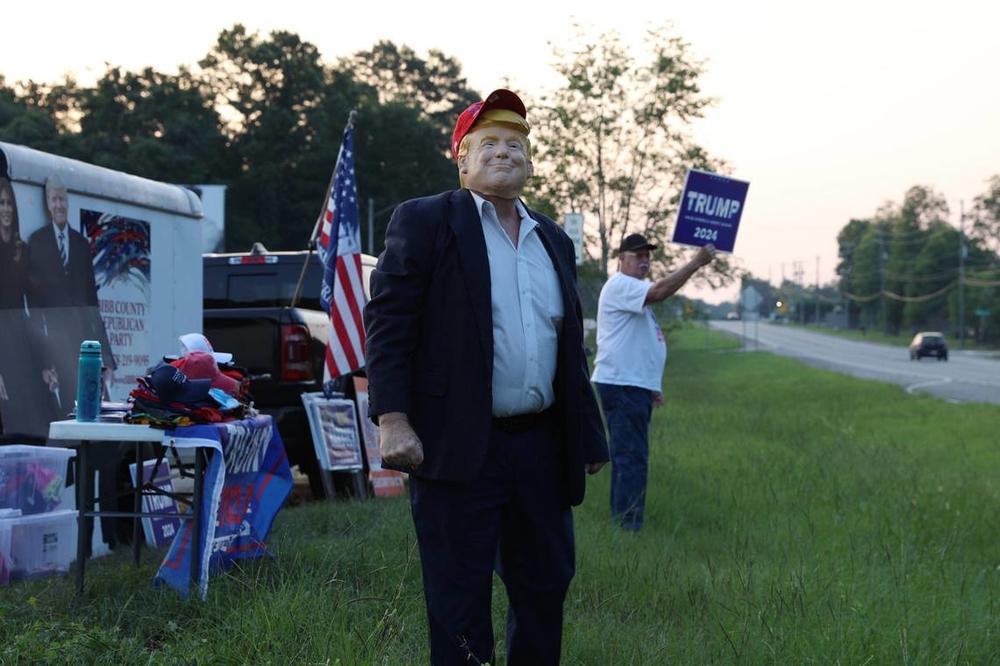 Bibb County Republican Party chairman David Sumrall stands in a Donald Trump mask on the side of Eisenhower Parkway on Monday, July 15, 2024, in Lizella, Georgia. A half dozen supporters, including members of the Bibb County Republican Party, gathered to show their support for former president Trump two days after an attempted assassination attempt on him in Pennsylvania. Katie Tucker/The Telegraph