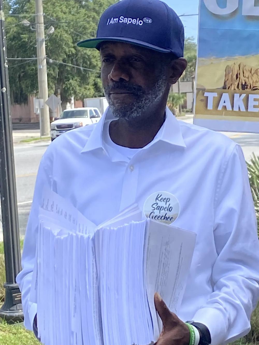Josiah “Jazz” Watts holds copies of the petitions with signatures requesting a referendum to repeal the new zoning ordinance affecting Hogg Hummock on Sapelo Island. Credit: Susan Catron/The Current GA