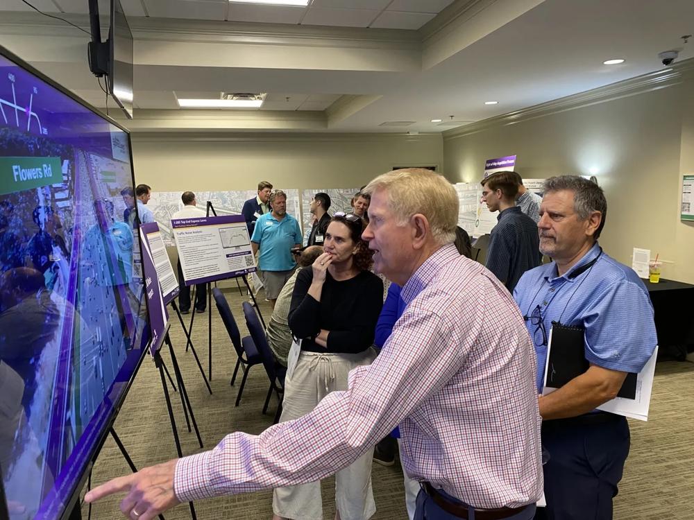 Attendees, including former Mayor Dennis Shortal (left) and Dunwoody Homeowners Association President Bob Fiscella watch a video that depicts the a visualization of the ai-285 Top End Express Lane in action. (Photo by Cathy Cobbs)