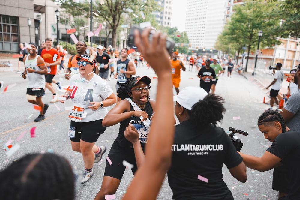 Members of the Atlanta Run Club wore custom shirts to the race and ran through confetti as they passed the "cheer station" during the 55th Peachtree Road Race on July 4, 2024.