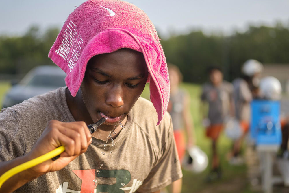 A football player in Macon, Georgia, drinks water during practice in August 2024.