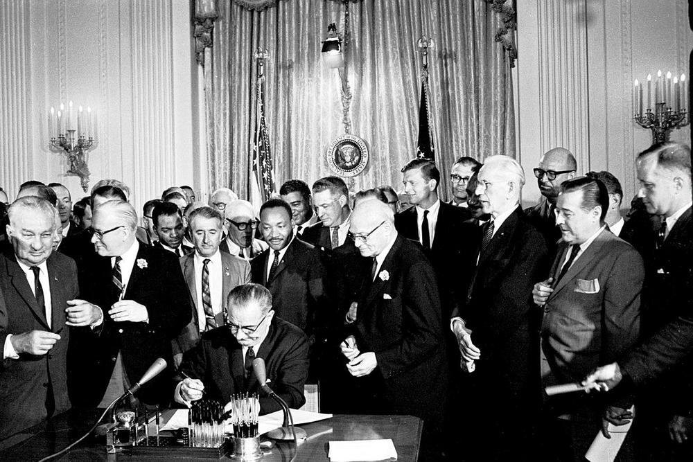 President Lyndon B. Johnson signing the Civil Rights Act surrounded by supporters including Martin Luther King Jr. (1964) 