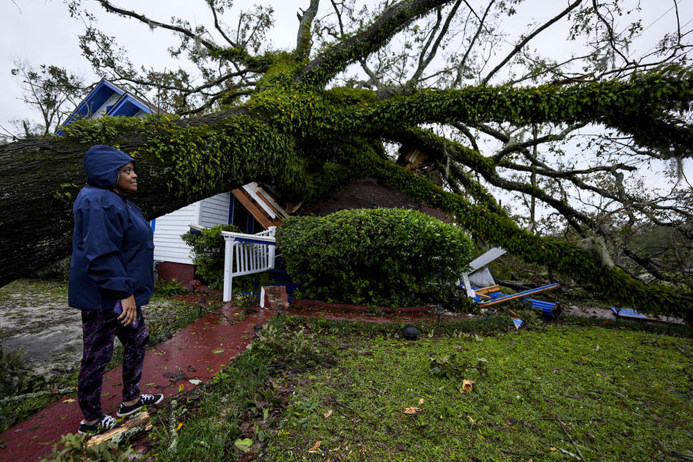 Rhonda Bell looks on after an Oak tree landed on her 100-year-old home after Hurricane Helene moved through, Friday, Sept. 27, 2024, in Valdosta, Ga.