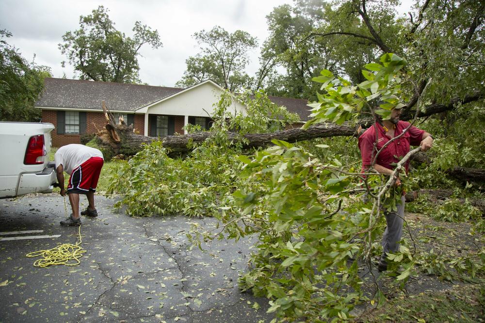 Neighbors Tyrone Allen, left, and Jared Middleton work together to clear a downed pecan tree from in front of Middleton’s home in Dublin, Ga. Hurricane Helene was likely still a category 1 hurricane when its eye passed over Dublin some 240 miles north of the Gulf of Mexico.