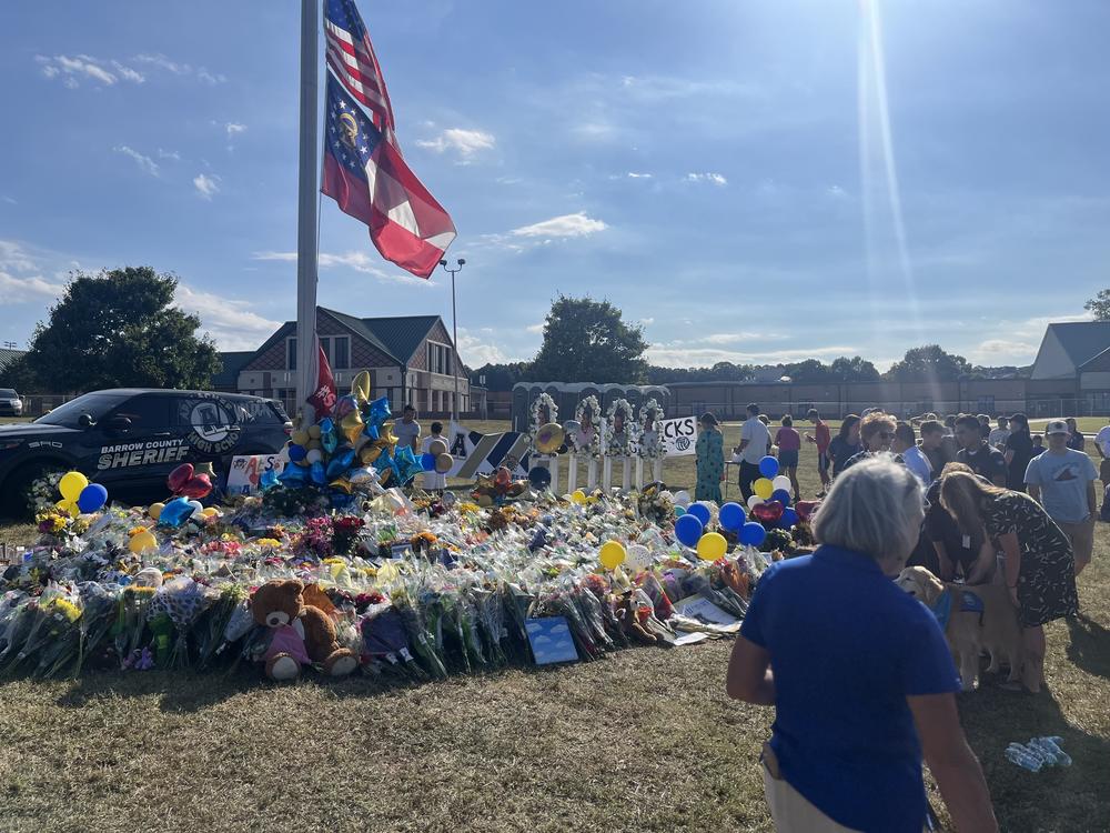 Community members and students gather around a flagpole on the Apalachee High School campus near Winder, Georgia, on Sept. 8, leaving flowers and messages to memorialize the four people killed in the Sept. 4 shooting there. 