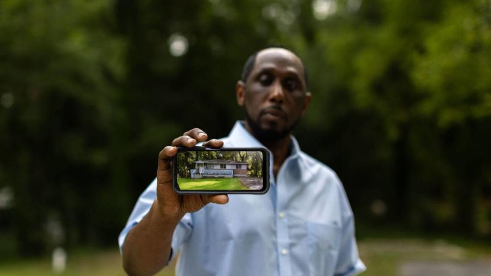 Eric Arnold, owner of 1151 Sunnydale Drive, holds a phone with a picture of what the house he was renovating used to look like before it got demolished by Macon-Bibb County. He’s filing a lawsuit against them for “unconstitutionally” destroying his house. Institute for Justice